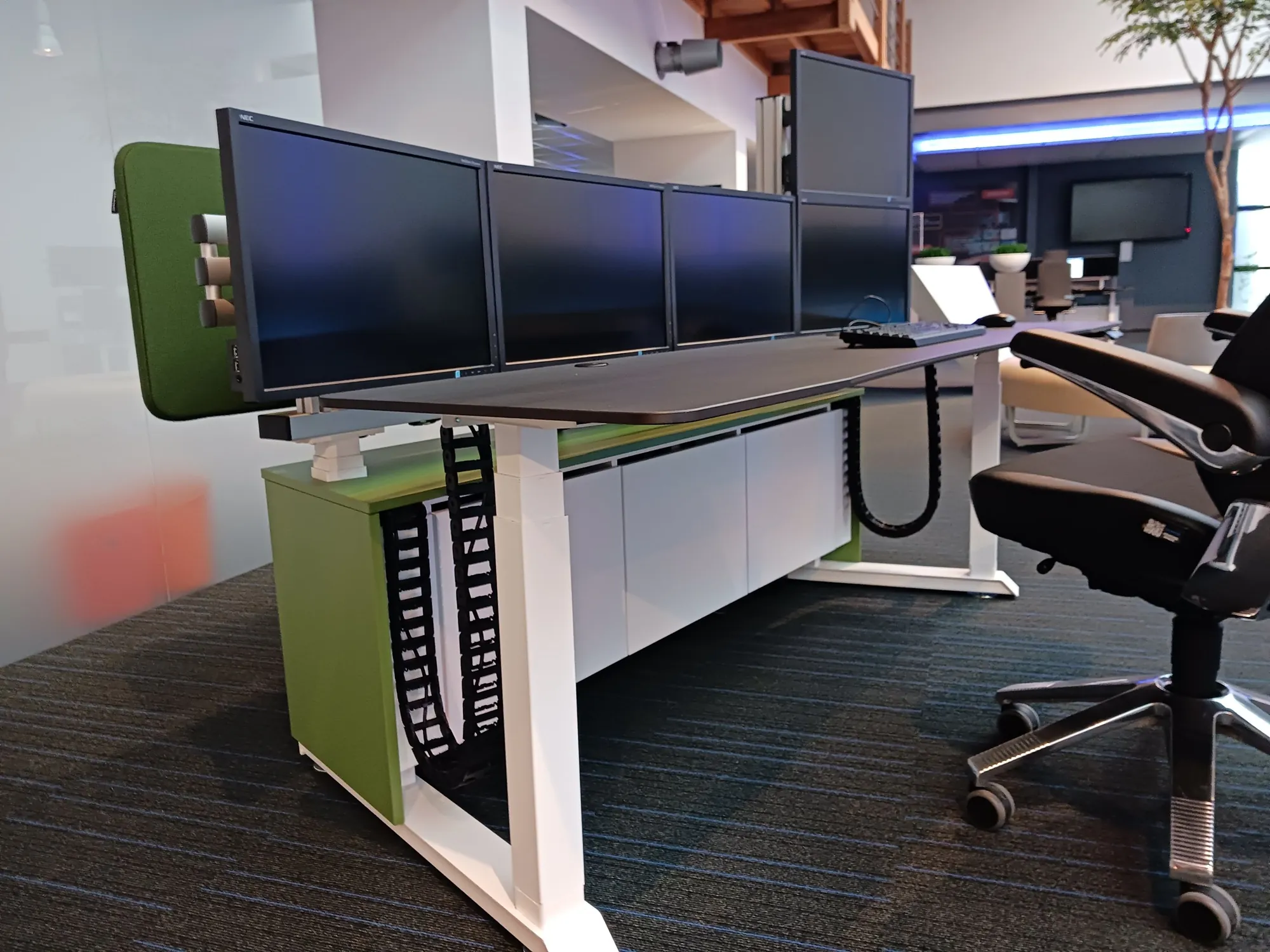 Electrically adjustable workstation with cable carriers for the cables to the monitors