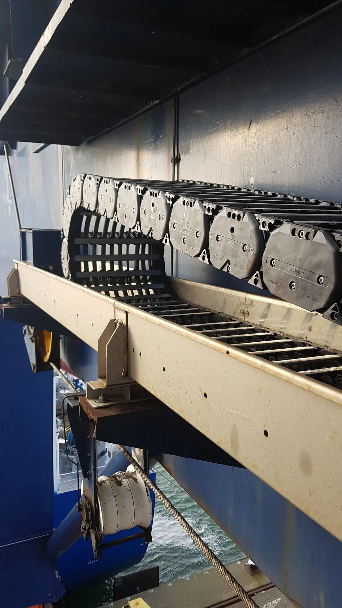 Heavy-duty cable carrier in the guide trough of a container crane