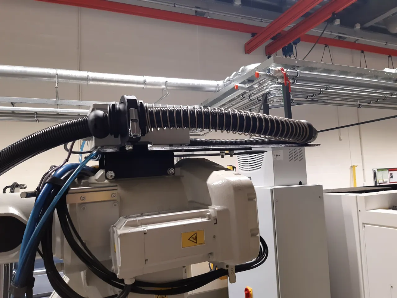 Protective hose with spring and retraction system on the robot