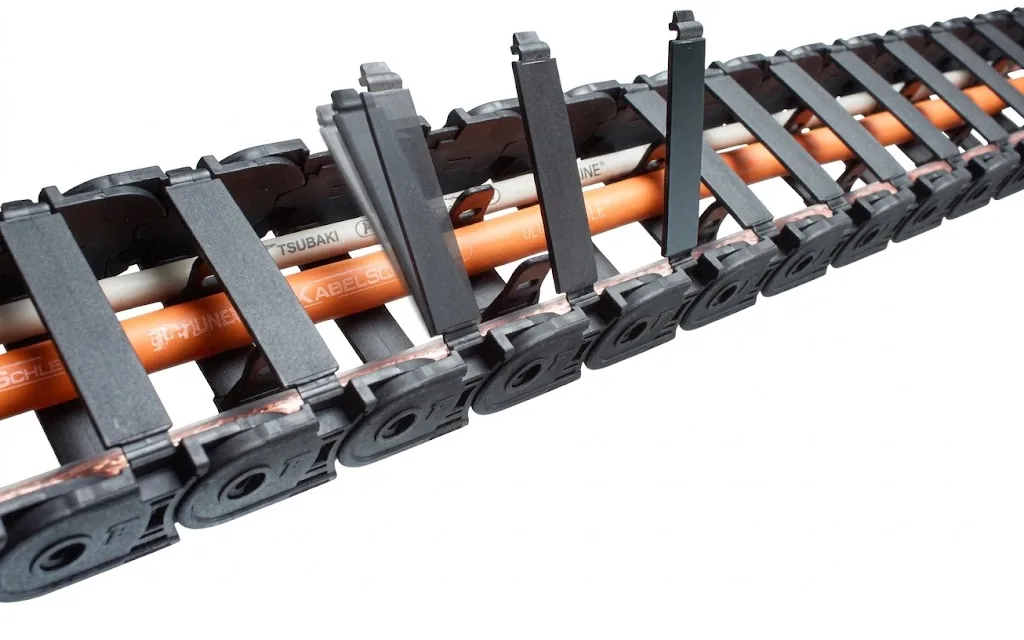 Black cable carrier with orange and white cables, divided by vertical and horizontal dividers