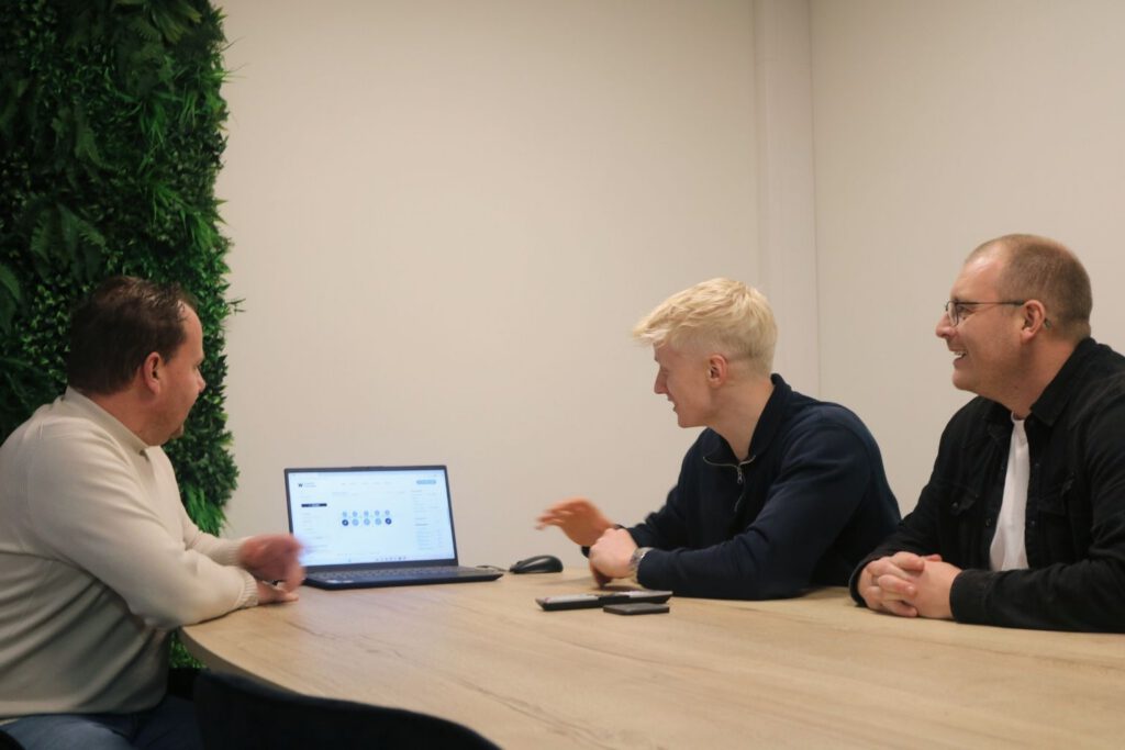 3 mederwerkers van Wisman Techniek overleg in kantoor ruimte bij laptop